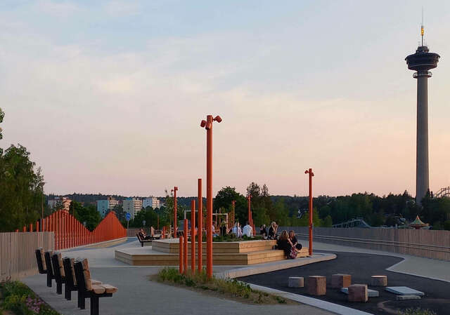 People sitting on wooden steps surrounding a planting area.