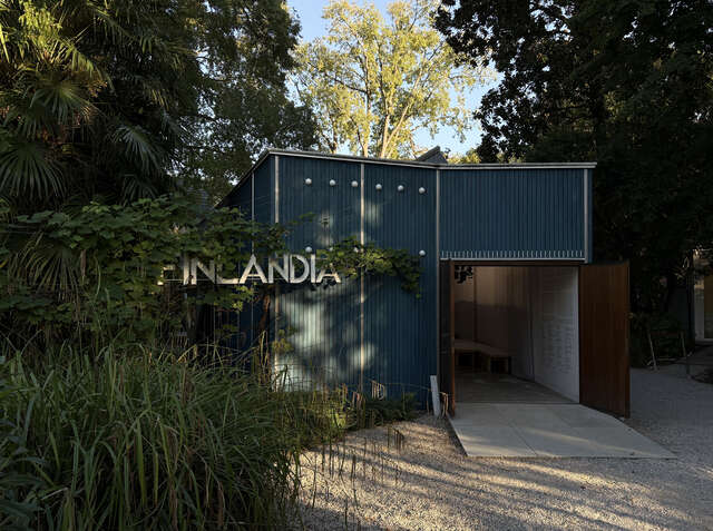 Pieni sininen paviljonki iltavalossa, edessä kirjaimet FINLANDIA.