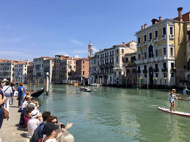 Kanaali, jonka rantakadulla istuu ihmisiä, vastapäätä vanhoja taloja.