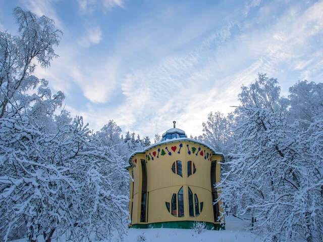 Keltainen lelun näköinen talo talvisessa maisemassa