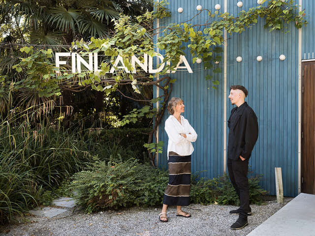 Woman and man standing in front of a blue wooden building