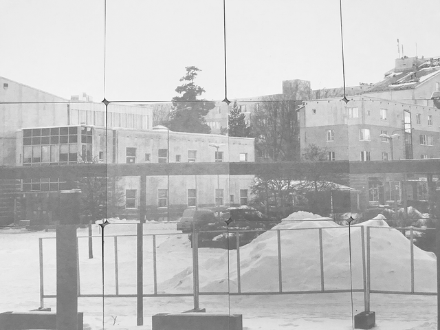 Kuva lasinalusista, jotka kuvastavat talvista lähiötä