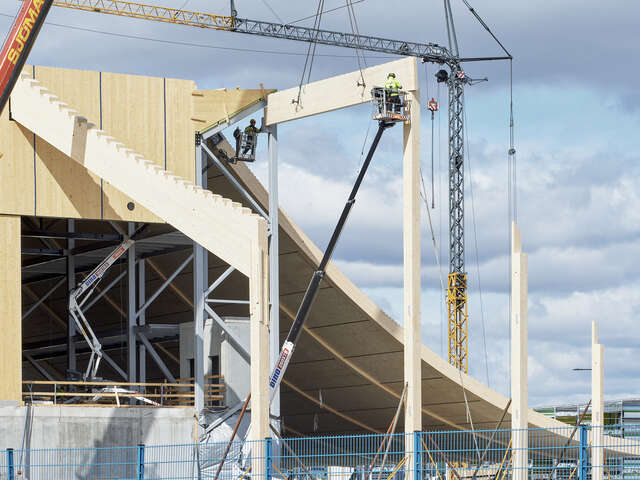 Large wooden building under construction with curved lip