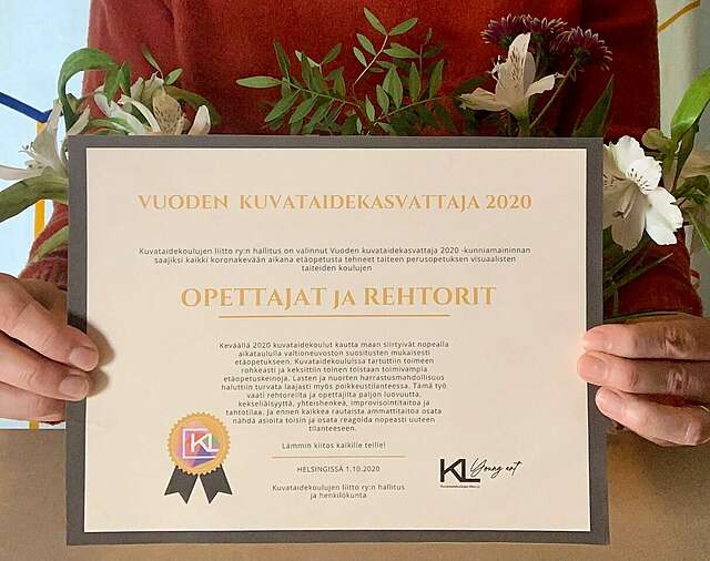 Henkilö pitää kädessään todistusta Vuoden kuvataidekasvattaja 2020 -kunniamaininnasta.