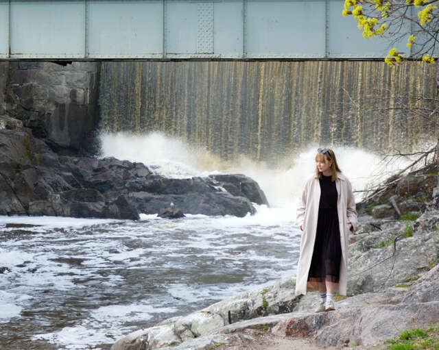 Woman walking around rocks beside a rapid.