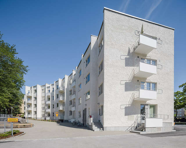 1950-luvun rapattu käärmeen muotoinen nelikerroksinen kerrostalo aurinkoisella säällä.