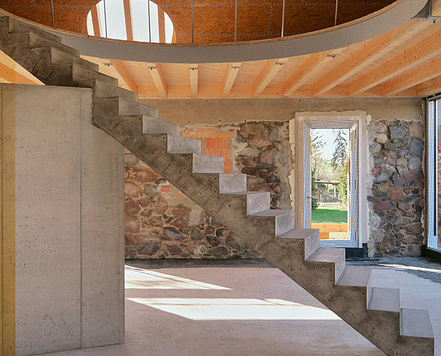 A bright two-story interior space with walls combining recycled aggregate and brick elements