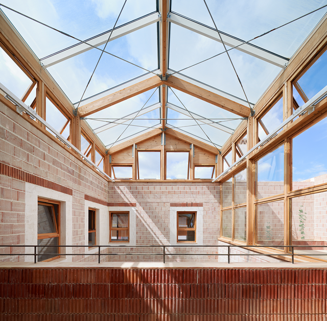 An inner courtyard topped with a glazed pitched roof, letting natural light into the spac