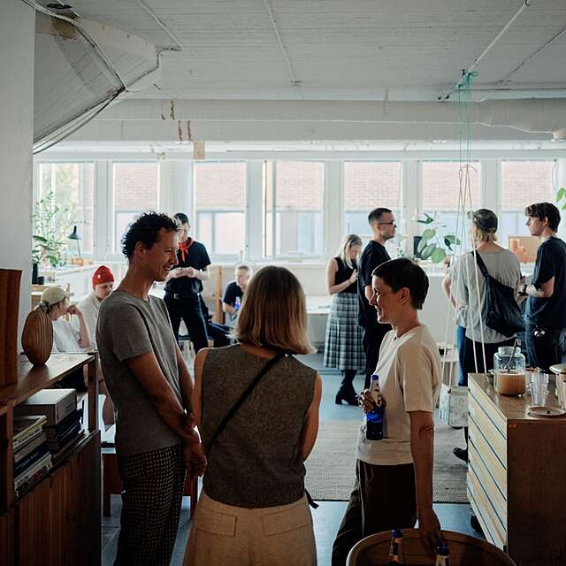 People having a conversation, with a row of windows in the background.