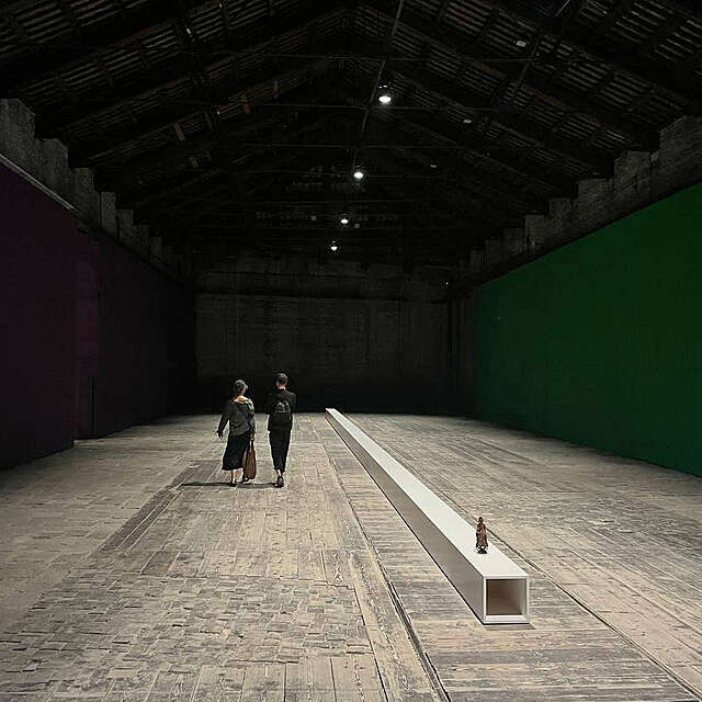 Photo of two people walking along a big hall space.