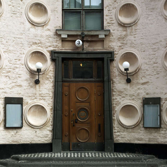 Klassistisen rakennuksen pääsisäänkäynnin rapattu vaaleanpunainen julkisivu ja iso ovi