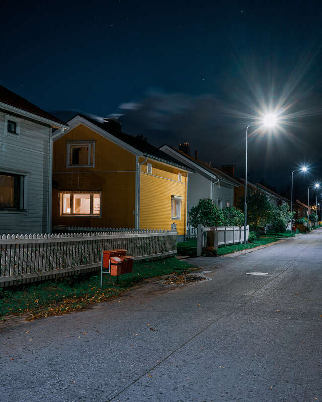 Katu, jonka varressa eri värisiä puutaloja kuvattuna pimeän aikaan.