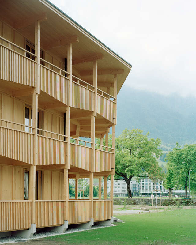 A three-storey wooden apartment building with terraces running around its facade