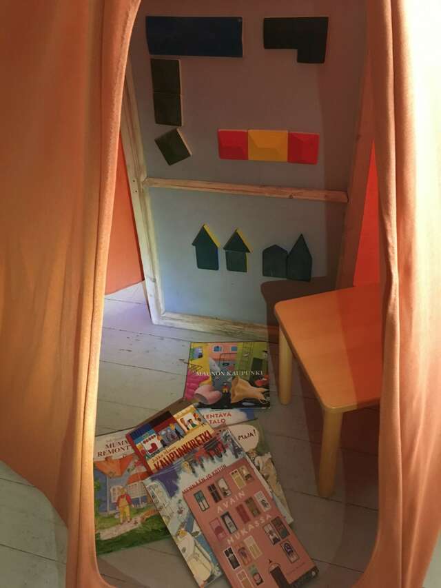 Leikkitila, lattialla puinen tuoli, lastenkirjoja ja taulu