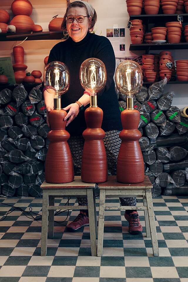 Hymyilevä nainen kolmen pöytälampun takana