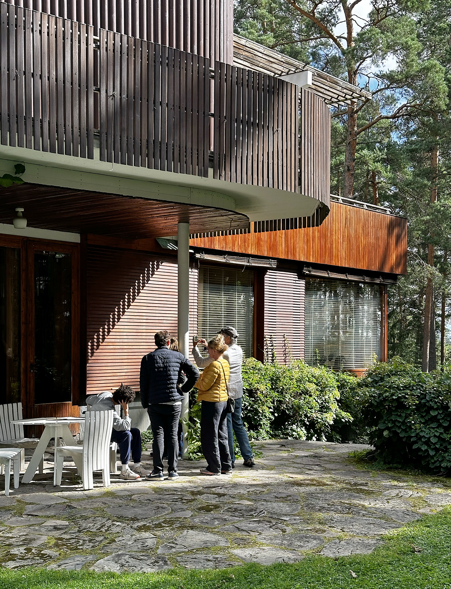 Joukko ihmisiä on selin kameraan rakennuksen ulkoterassilla.