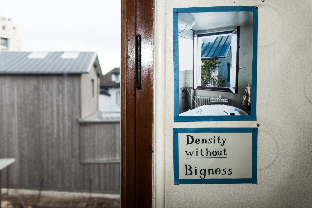 Seinällä ikkunan karmin vieressä juliste, jossa kuva avonaisesta sekä teksti "Density without Bigness", tiiviys ilman suuruutta.