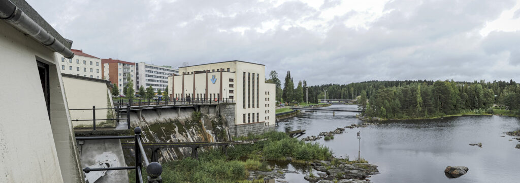 Panoraama, jossa näkyy pato ja kauempana voimala kaupungin edessä joen rannalla.